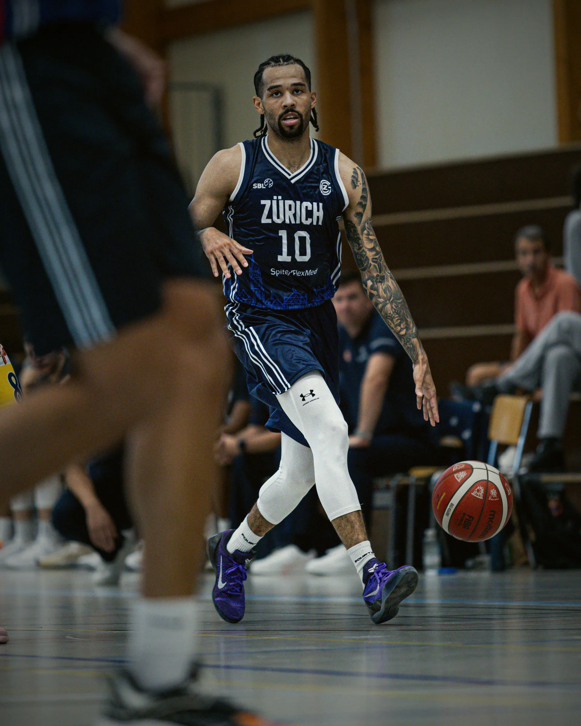 Spieler mit der Nummer 10 im dunkelblauen Auswärtstrikot dribbelt über das Feld