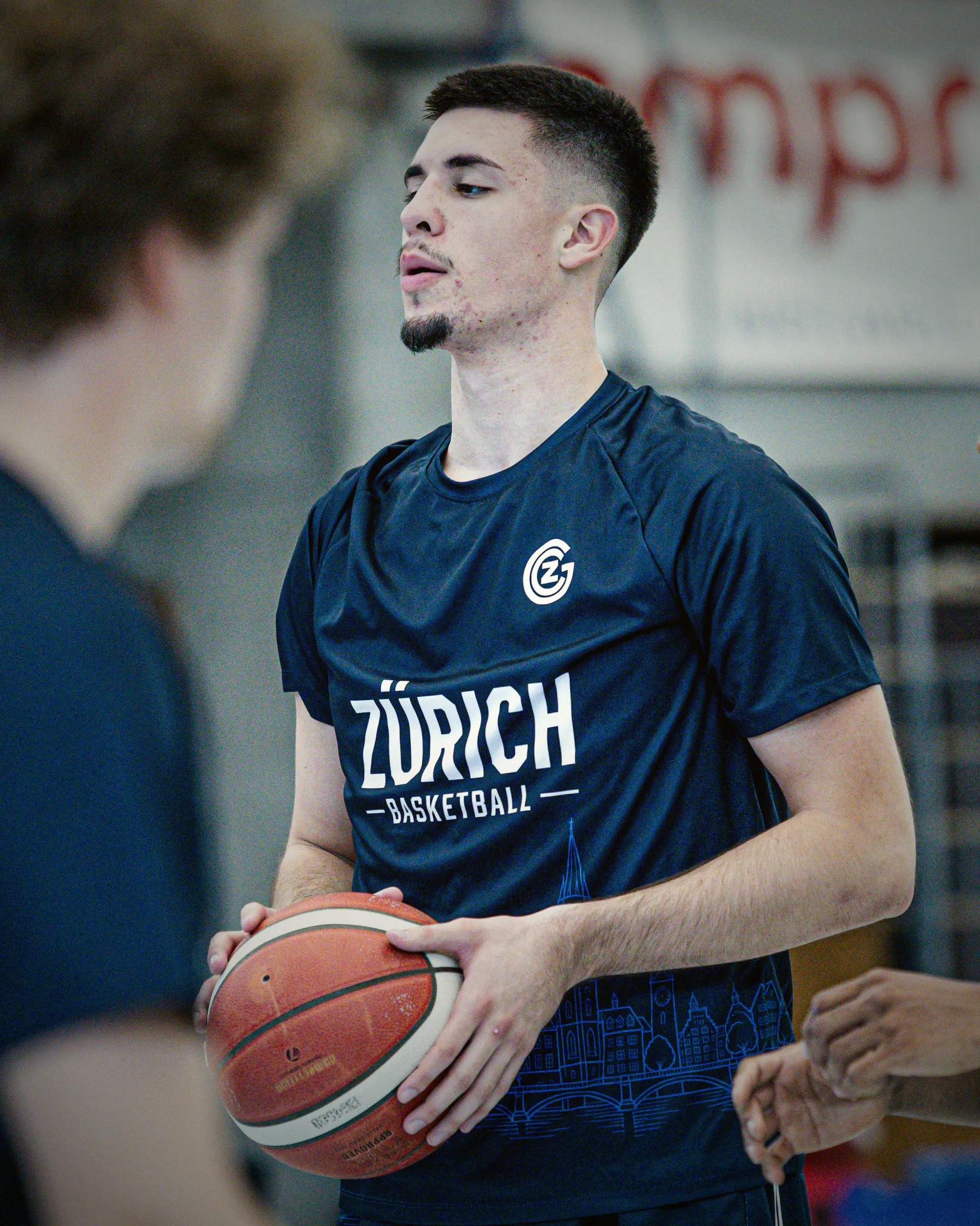 Spieler im dunkelblauen Warm-up Shirt mit Zürich-Schriftzug und Skyline, Ball in den Händen