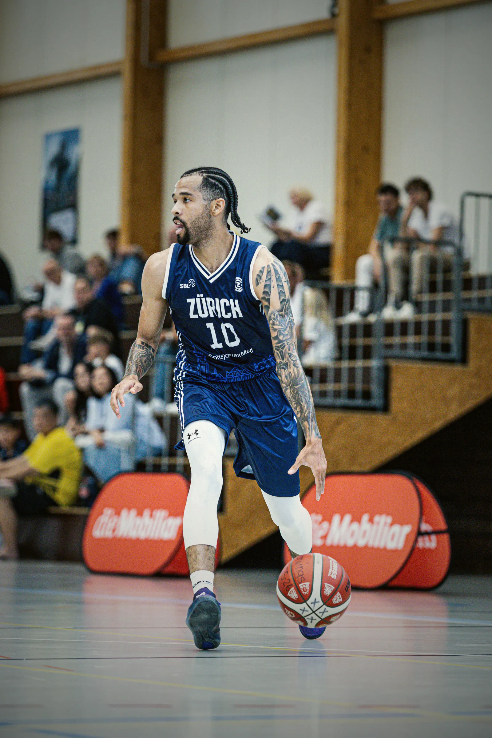 Spieler mit der Nummer 10 im dunkelblauen Auswärtstrikot dribbelt vor der Tribüne