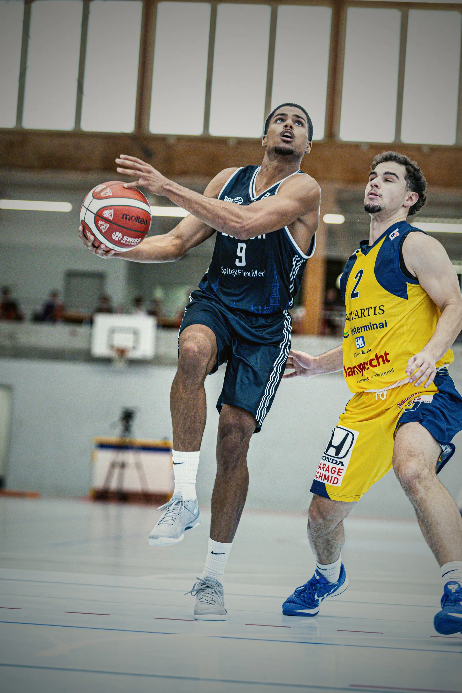 Spieler mit der Nummer 9 im dunkelblauen Auswärtstrikot zieht zum Korb