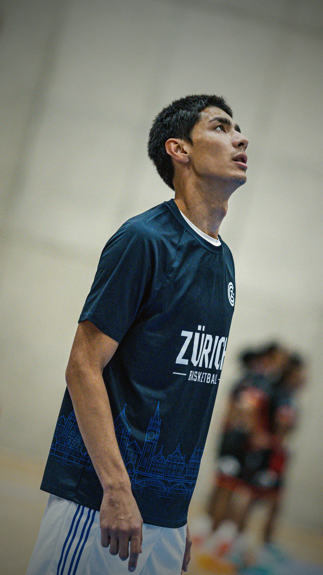 Spieler im dunkelblauen Warm-up Shirt schaut zum Korb, Seitenansicht
