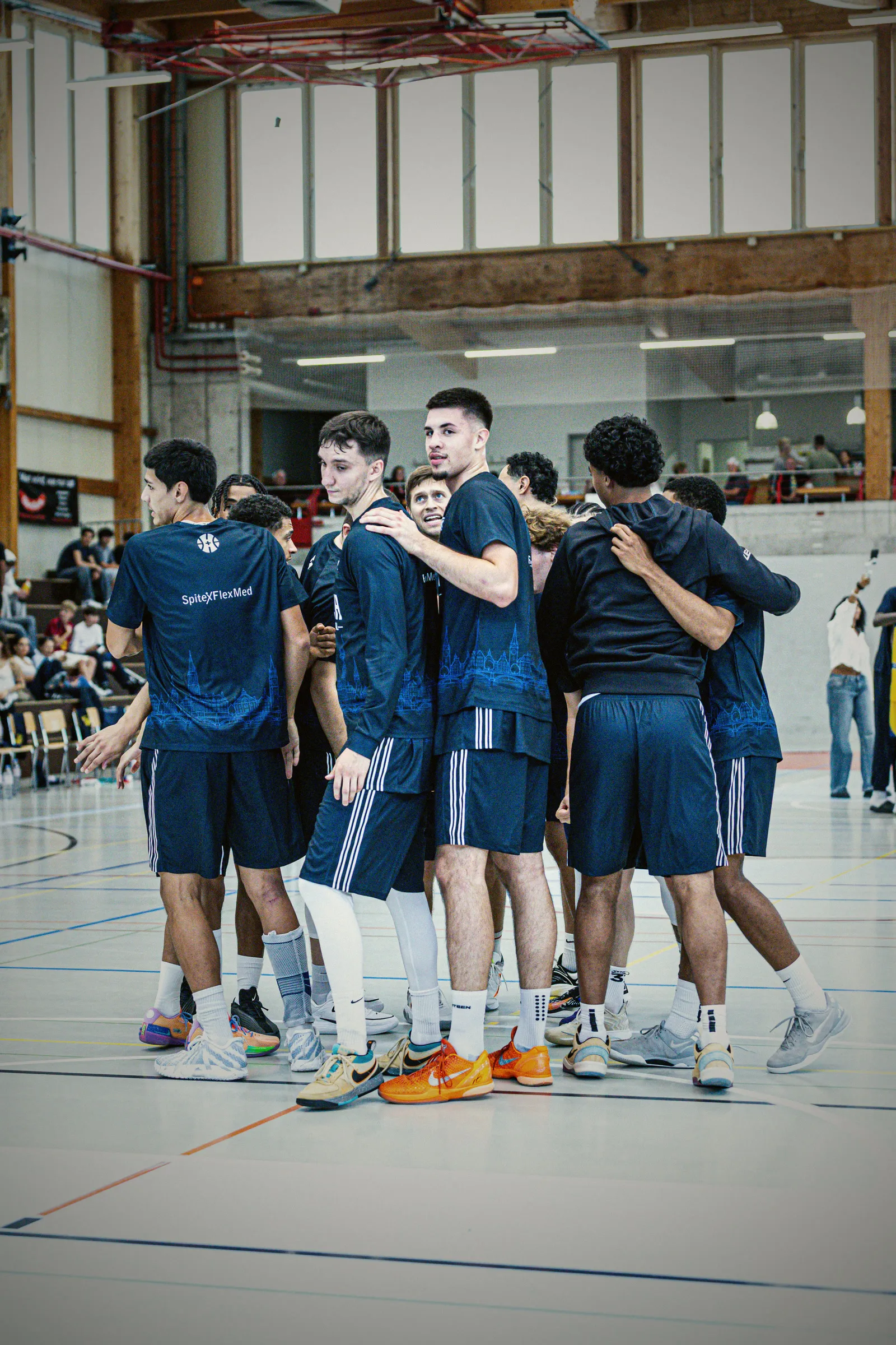 Das Team von GC Basketball im dunkelblauen Auswärtstrikot bildet einen Kreis