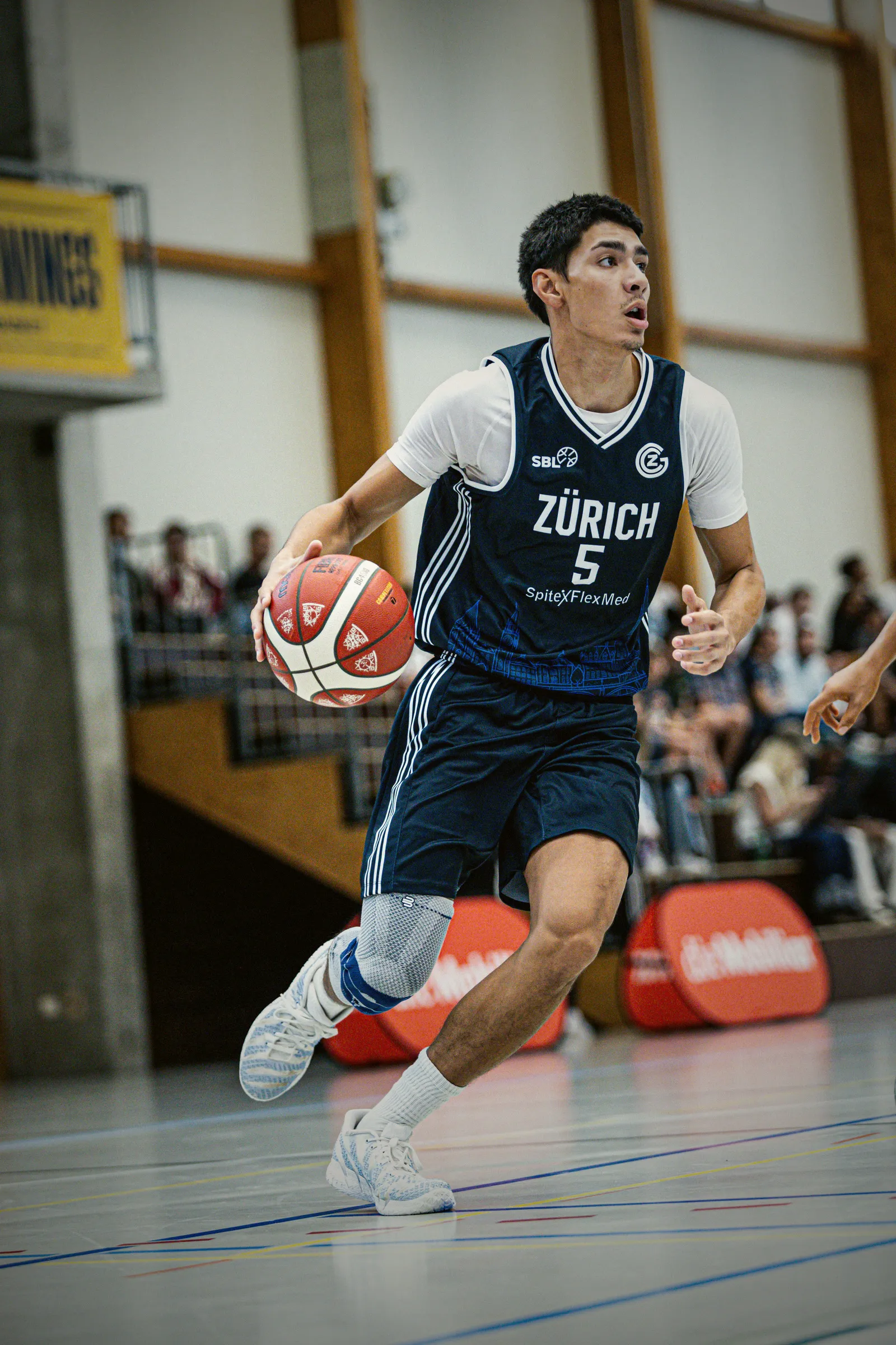 Spieler mit der Nummer 5 im dunkelblauen Auswärtstrikot dribbelt nach vorne