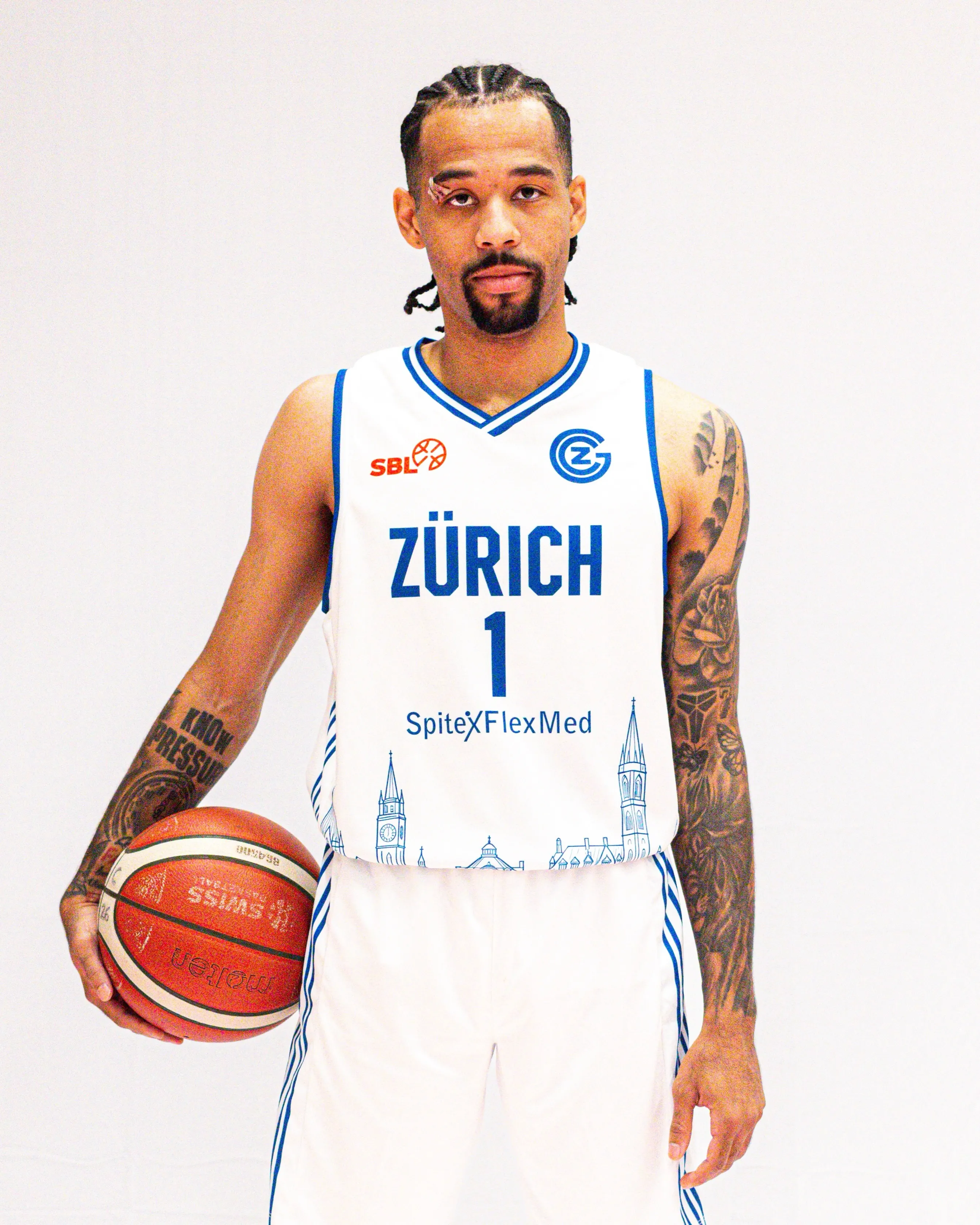 Spieler von GC Basketball im weissen Heimtrikot mit Zürcher Skyline, Ball unter dem Arm